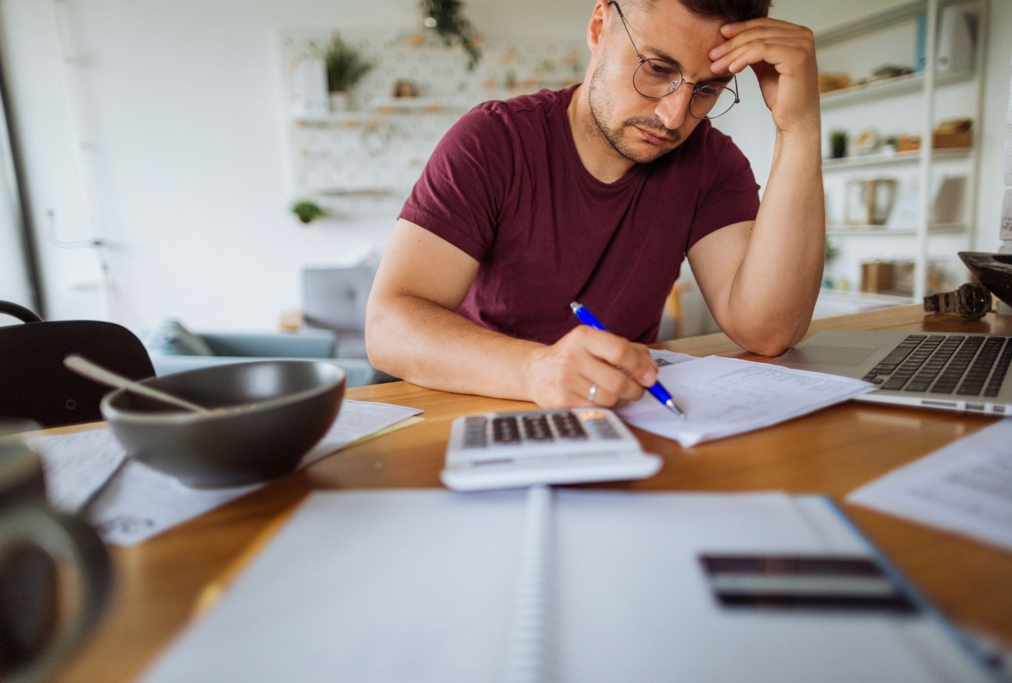 Man pays bills at a table covered in papers
