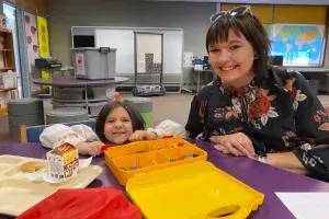 female teacher with young student at art table.