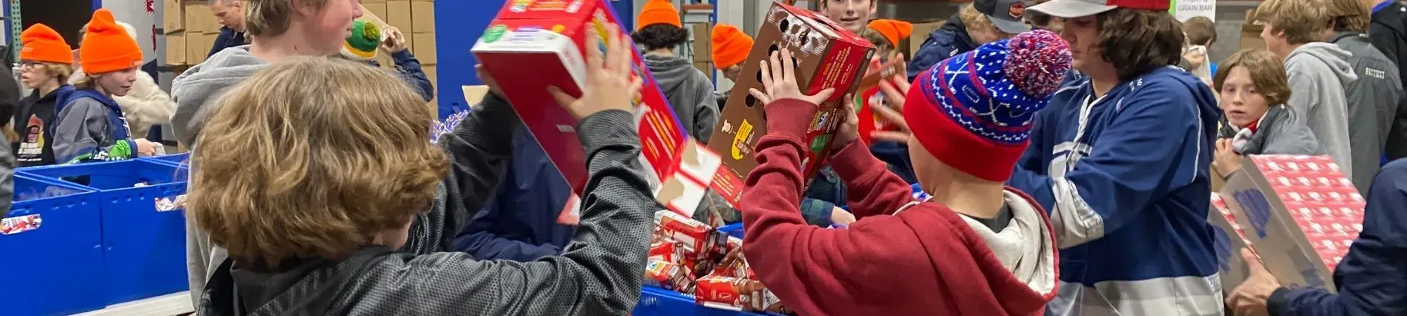 Student open boxes of food to pack into Buddy Backpacks for their classmates at-risk of hunger.