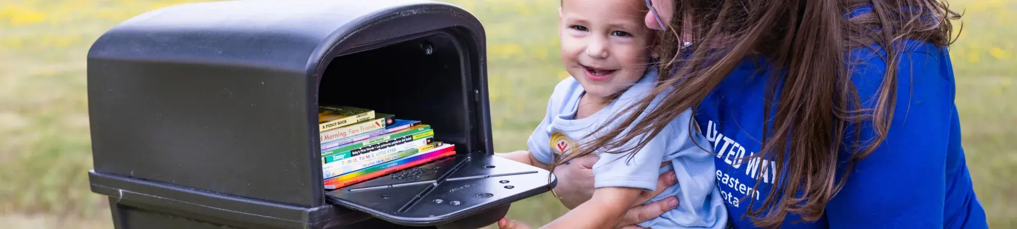 Mother and child open a mailbox full of Imagination Library books
