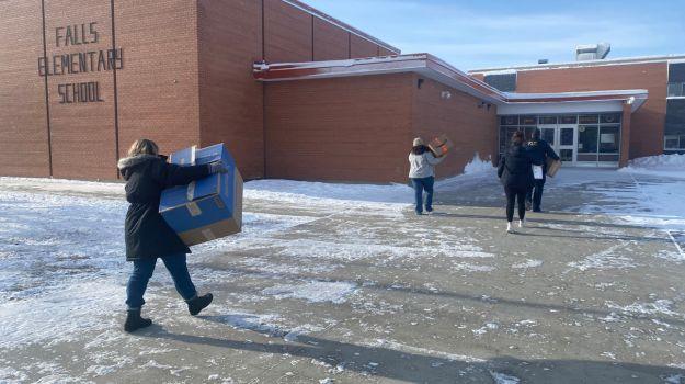 Volunteers carry boxes of winter clothing into Falls Elementary School.