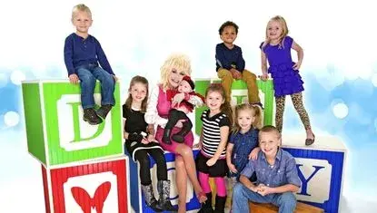 Dolly Parton smiles with children seated on blocks for an Imagination Library photo