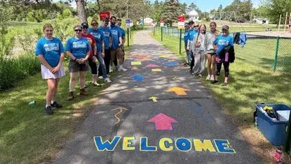 Volunteers stand by the newly painted Born Learning Trail in Chisholm